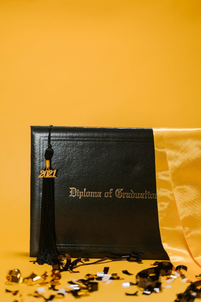 Close-up of a graduation diploma with a 2021 tassel, on a vibrant yellow backdrop.